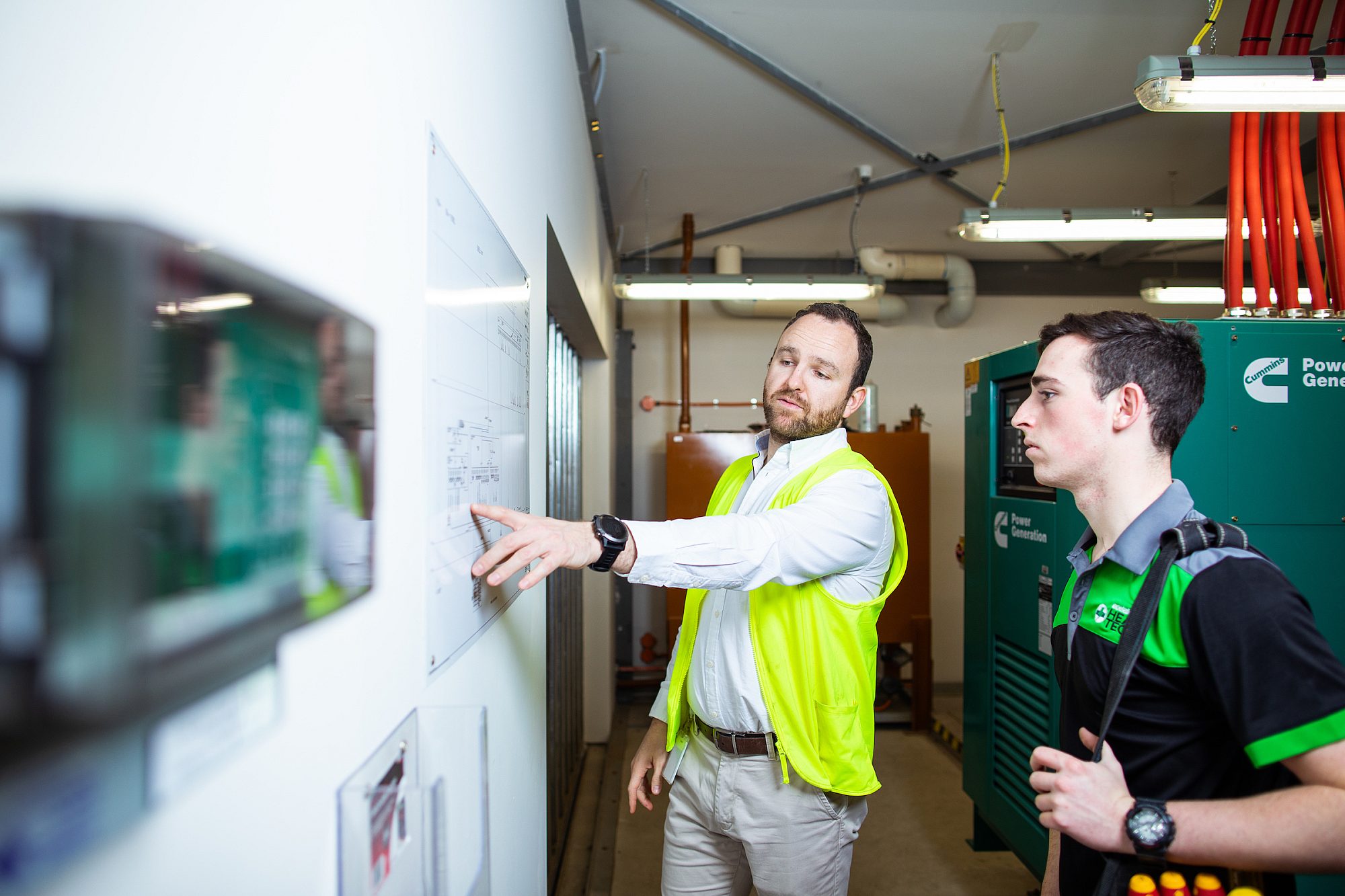 Teacher showing student blueprint on the wall.